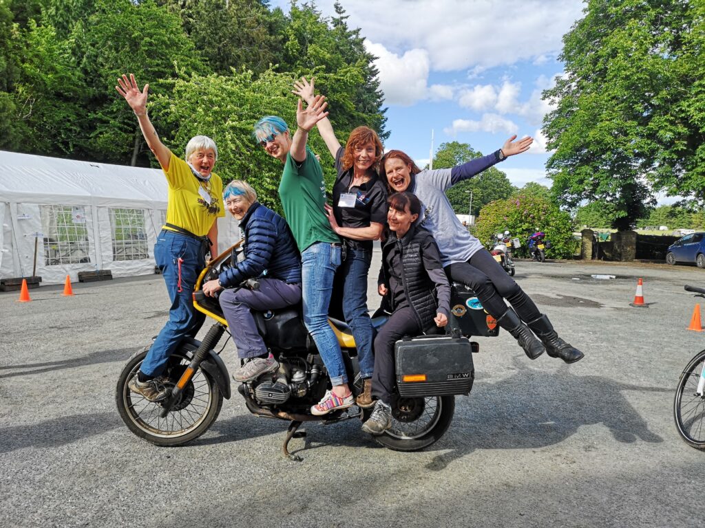 Six ladies on a single motorbike, happy and simling.